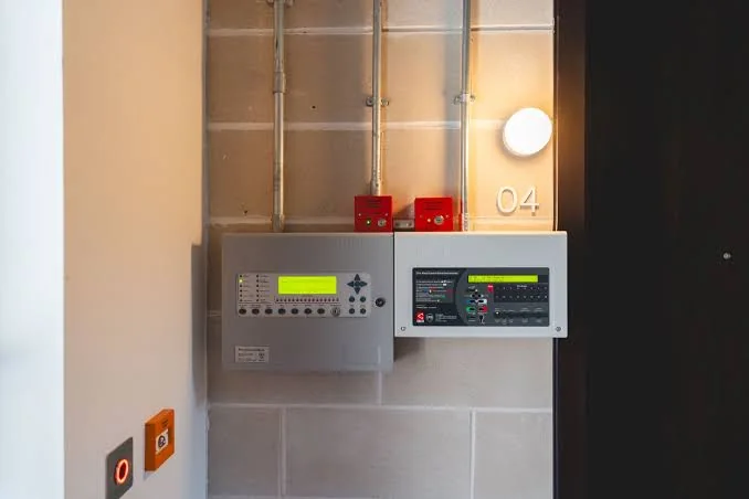 Two fire alarm control panels mounted in a service area with manual call points
