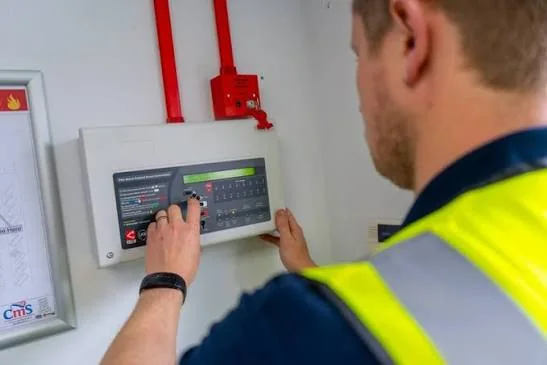 An engineer operating the keypad of a fire alarm control panel