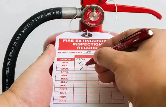 A hand completing an extinguisher inspection record tag