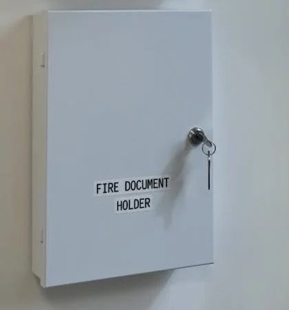 A locked fire document holder mounted beneath a fire alarm panel