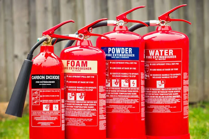 A range of red fire extinguishers: carbon dioxide, foam, powder and water
